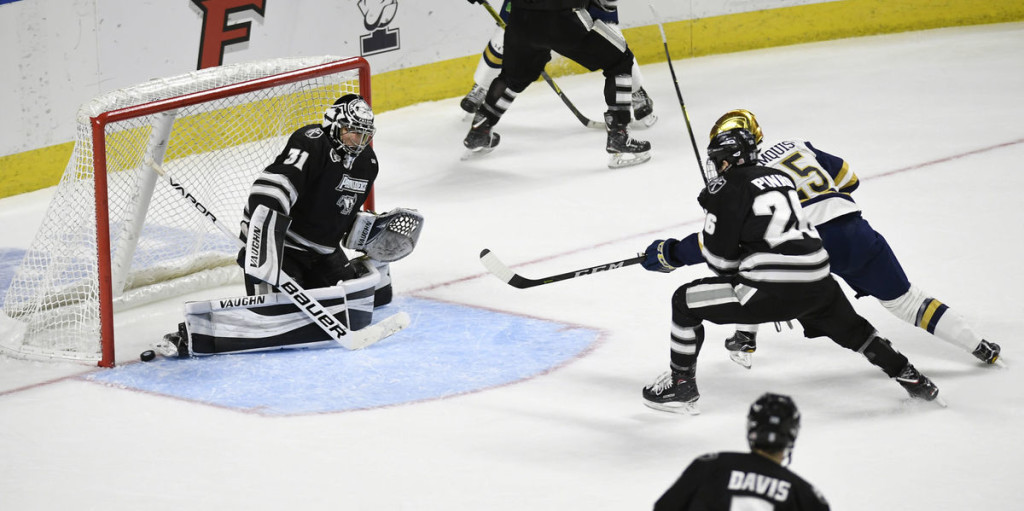 Notre Dame junior forward Dylan Malmquist, of Edina,  MN. (#25 in white, shielded by Pinho of Providence, #25 in black), scored this last minute goal Saturday (note puck at bottom left of goal) to give Notre Dame a 2-1 win over Providence College, and to advance them to the Frozen Four.