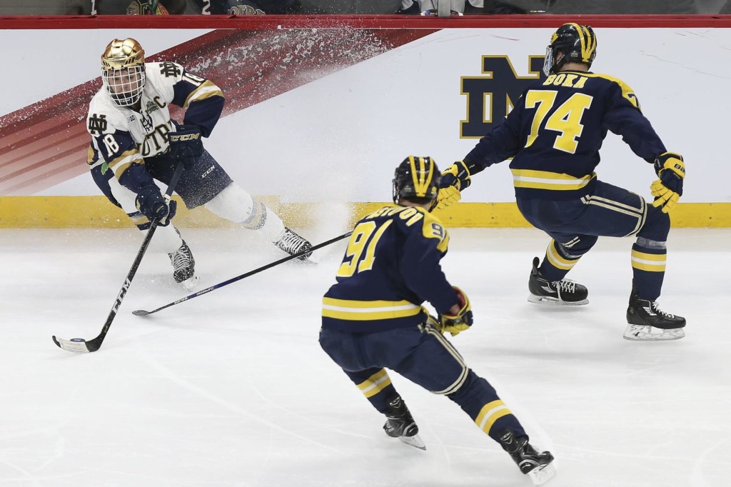 Notre Dame senior forward Jake Evans, of Toronto, ONT., controls the puck against two Michigan defenders during second period play yesterday in the Frozen Four in St. Paul, MN.  Evans scored two goals in the game, including the last-second game winner, advancing Notre Dame to the NCAA Championship Game against Minnesota-Duluth tomorrow, Saturday, April 7th, at 4:30pm Pacific Time, scheduled for ESPN.